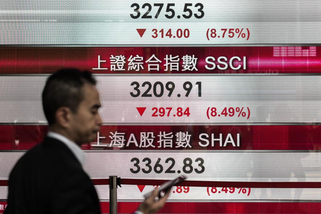 A man checks his cell phone in front of an electronic board displaying stock market information in Hong Kong on Aug. 24, 2015.