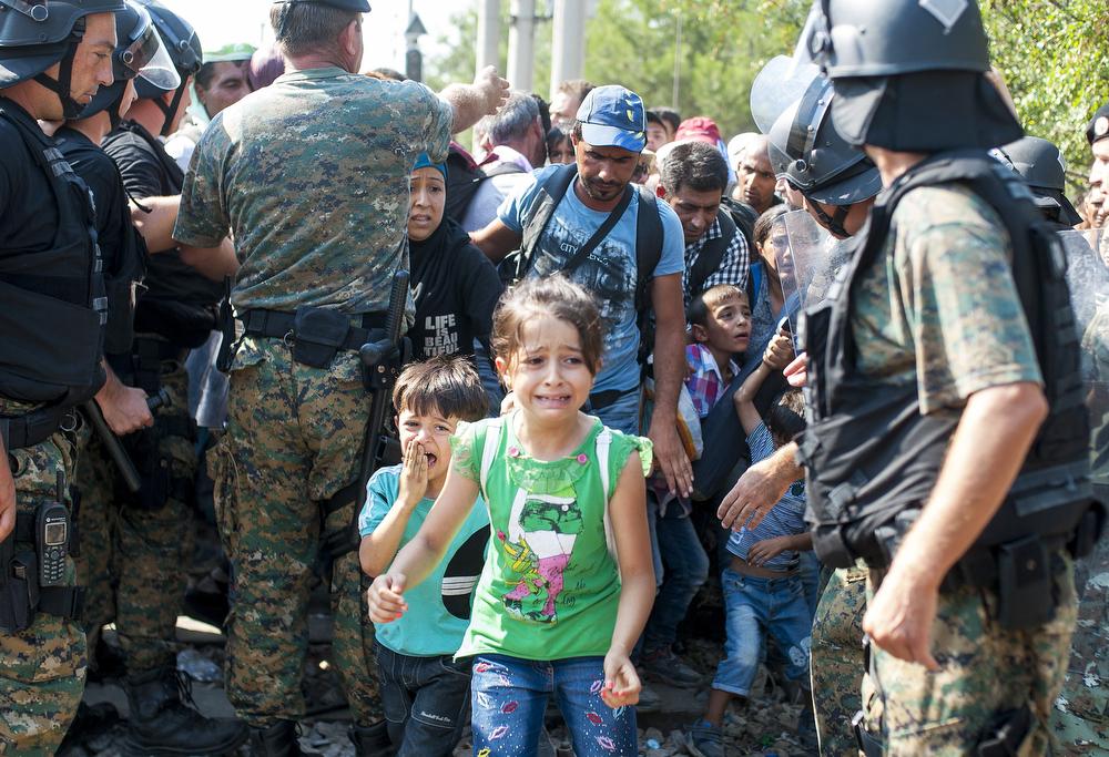 Migrants walk past police while trying to cross the Greece-Macedonia border on Aug. 26, 2015.