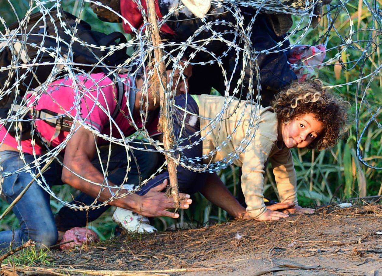 Migrants go under Hungary border fence