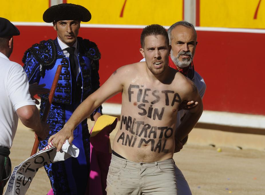 A man is detained after jumping into the bullring with the sentence 'Fiesta without animal abuse' written on his body during the seventh corrida of the San Fermin Festival in Pamplona, on July 13, 2015.