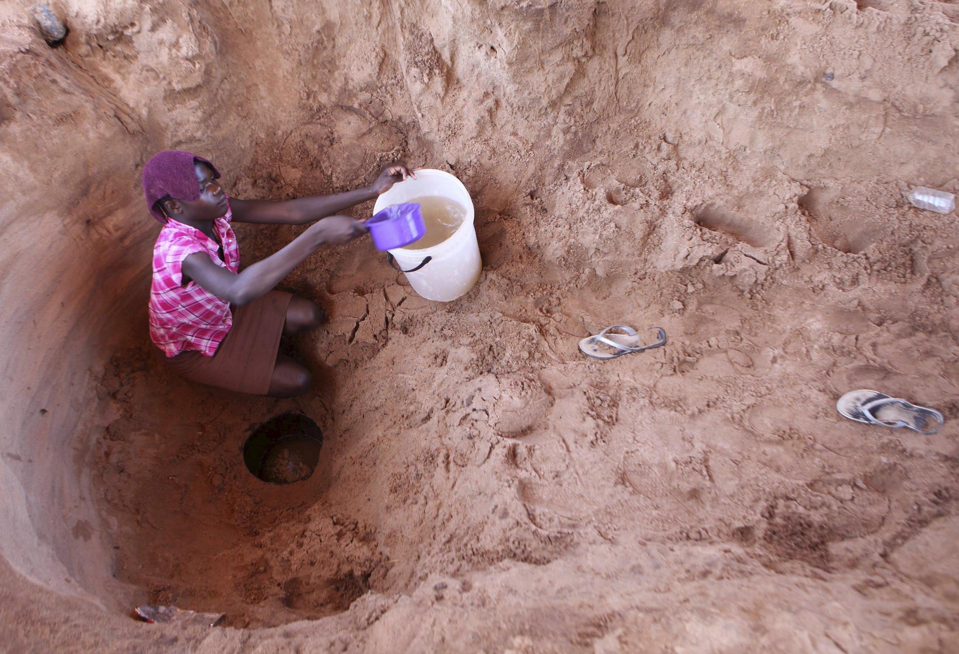 A woman fetches drinking water from a well along a dry Chemumvuri river near Gokwe, Zimbabwe.