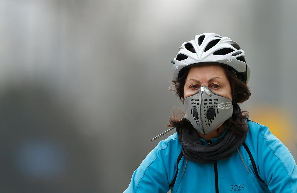 A cyclist wears a mask with an air filter as she cycles through Hyde Park in London on April 3, 2014.