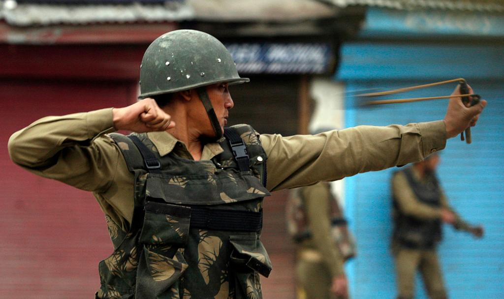 An Indian policeman uses a slingshot to throw stones at Kashmiri protesters during an anti-election protest in Srinagar on May 8, 2009.