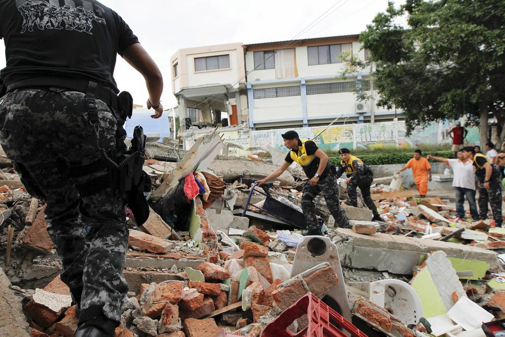 Red Cross members, military and police officers work at a collapsed area after an earthquake struck off Ecuador's Pacific coast, at Tarqui neighborhood in Manta on April 17, 2016.