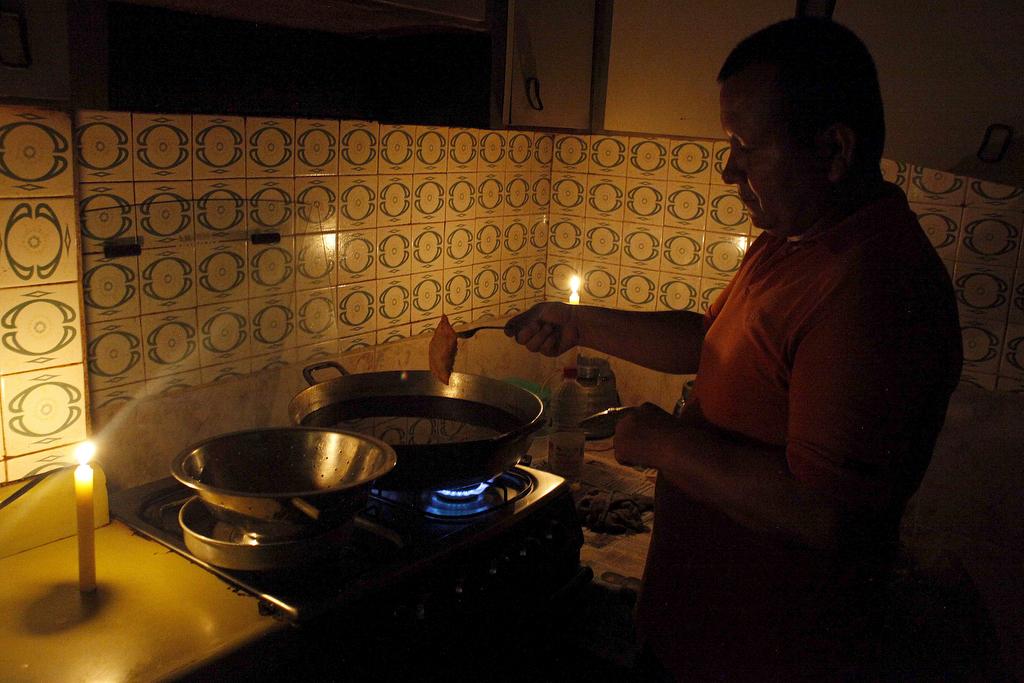A man cooks near lit candles at his home during a power cut in San Cristobal, in the state of Tachira, Venezuela, on April 25, 2016.