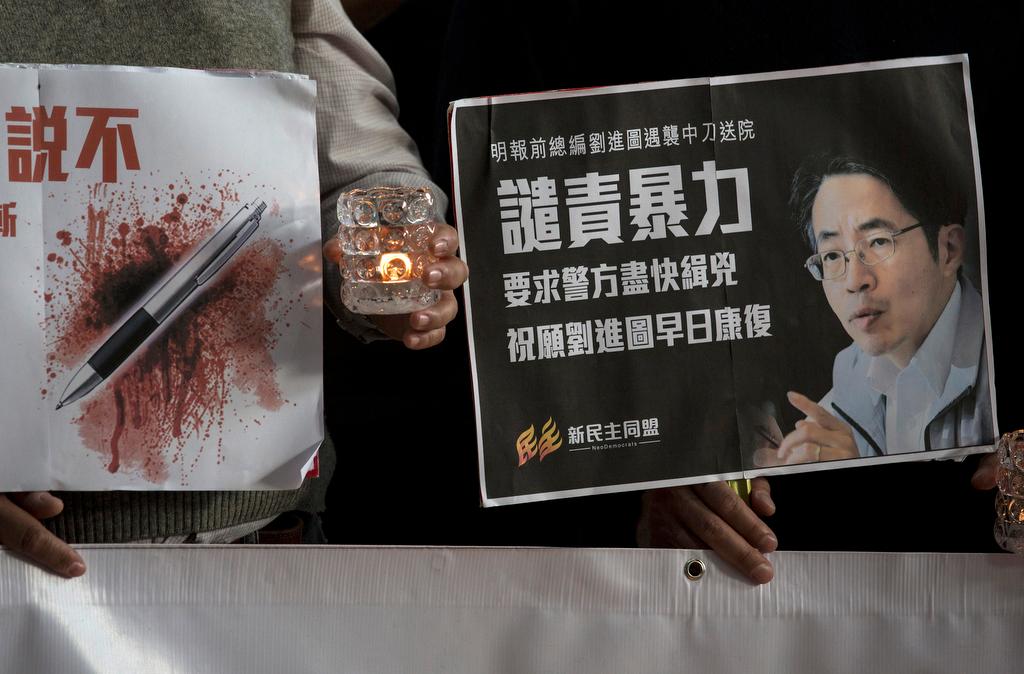 Pro-democracy activists hold a sign with an image of former chief editor of the Ming Pao daily Kevin Lau Chun-to as they attend a candlelight vigil to urge the police to solve the stabbing incident involving Lau, at a hospital in Hong Kong on Feb. 26, 201
