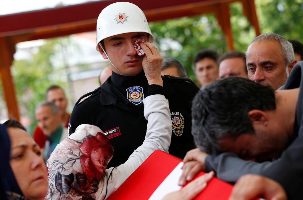 A woman wipes the tears of an honour guard as he stands next to the coffin of police officer Kadir Cihan Karagozlu who was killed in Tuesday's car bomb attack on a police bus, at Fatih mosque in Istanbul, Turkey, June 8, 2016.