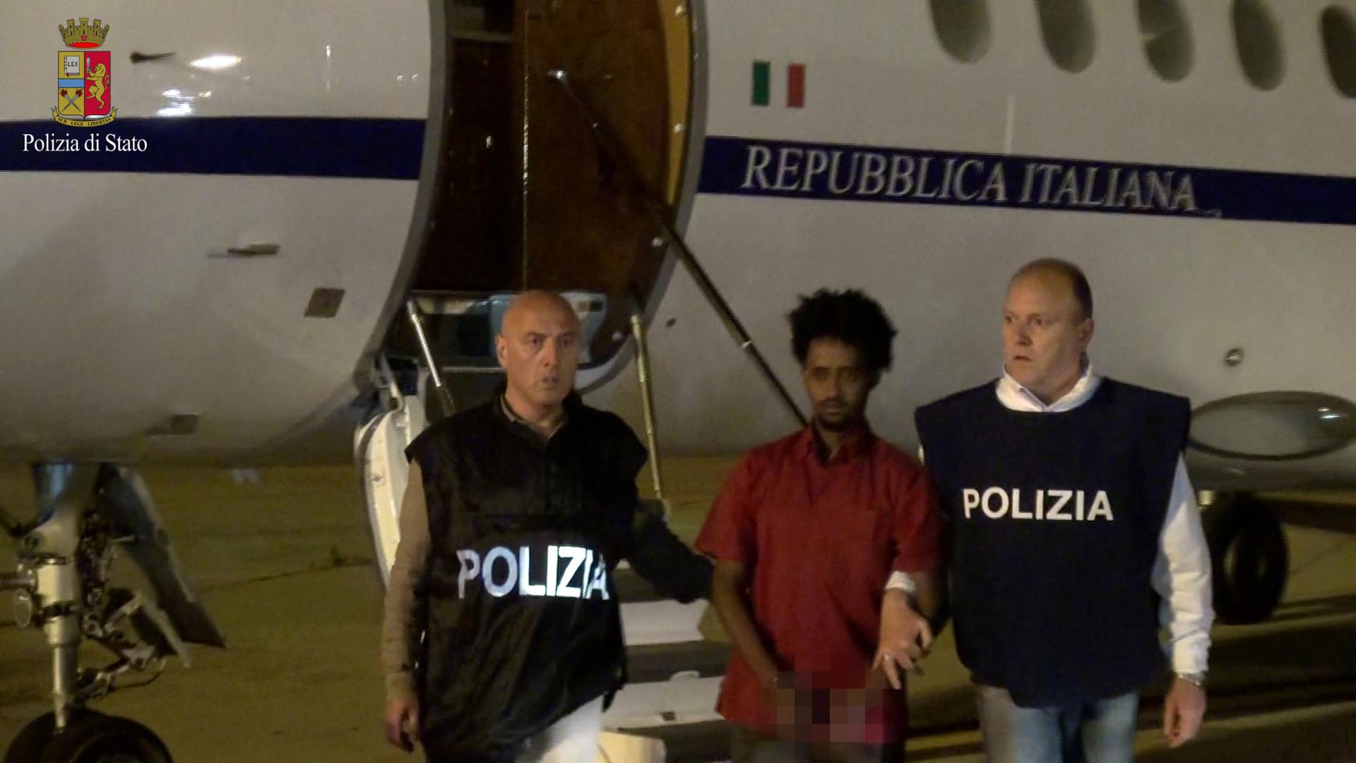 Medhanie Yehdego Mered, 35, is pictured with Italian policemen as they land at Palermo airport, Italy, following his arrest in Khartoum, Sudan, on May 24. The photo was released on June 8 by the Italian Police Department.