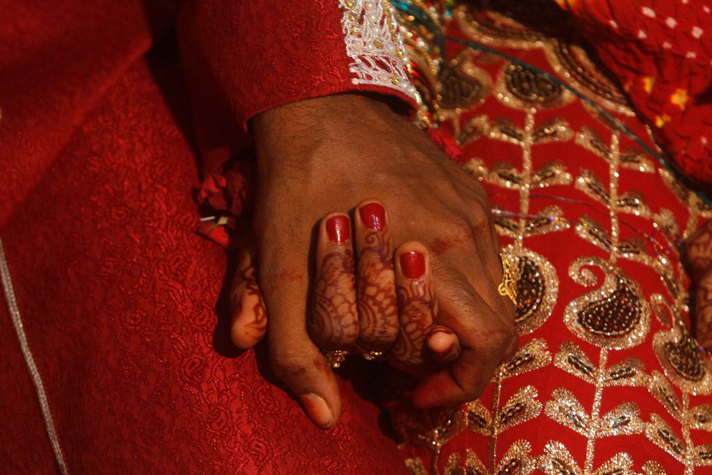 A bride and groom hold hands as they sit together during a mass marriage ceremony held in Karachi on Nov. 30, 2013.