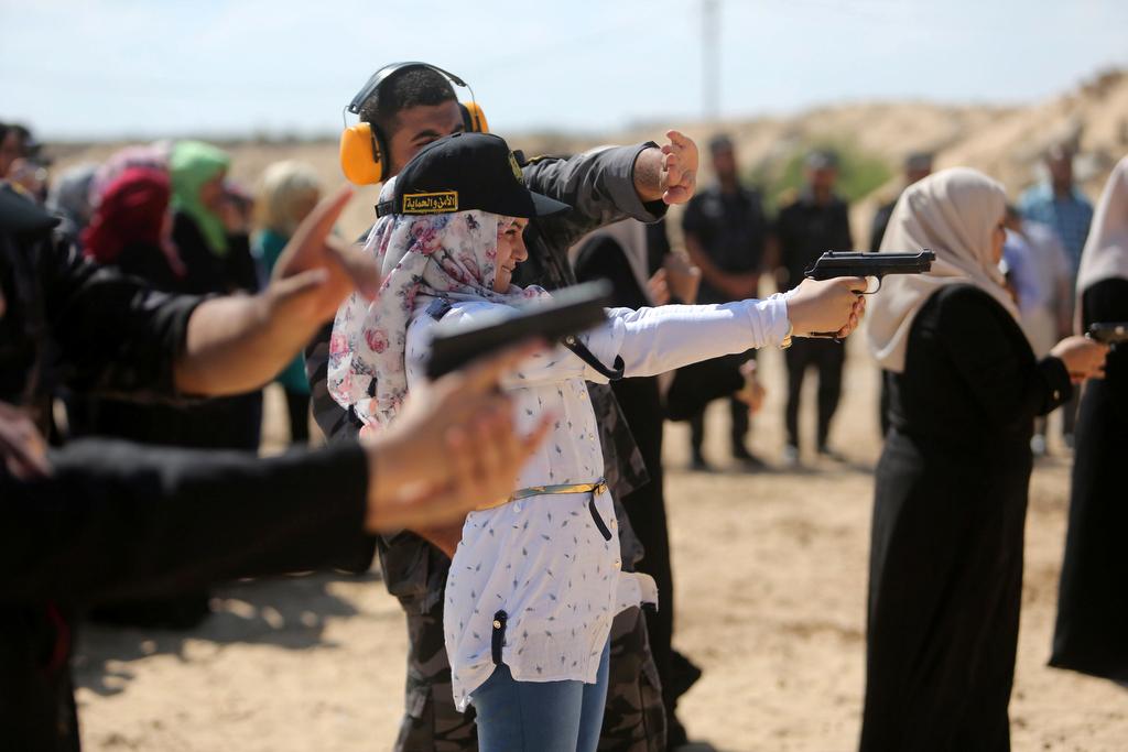 A Palestinian girl aims a pistol as she prepares to fire at a target during a training session for the families of Hamas officials, organized by Hamas-run Security and Protection Service, in Khan Younis in the southern Gaza Strip July 24, 2016. 
