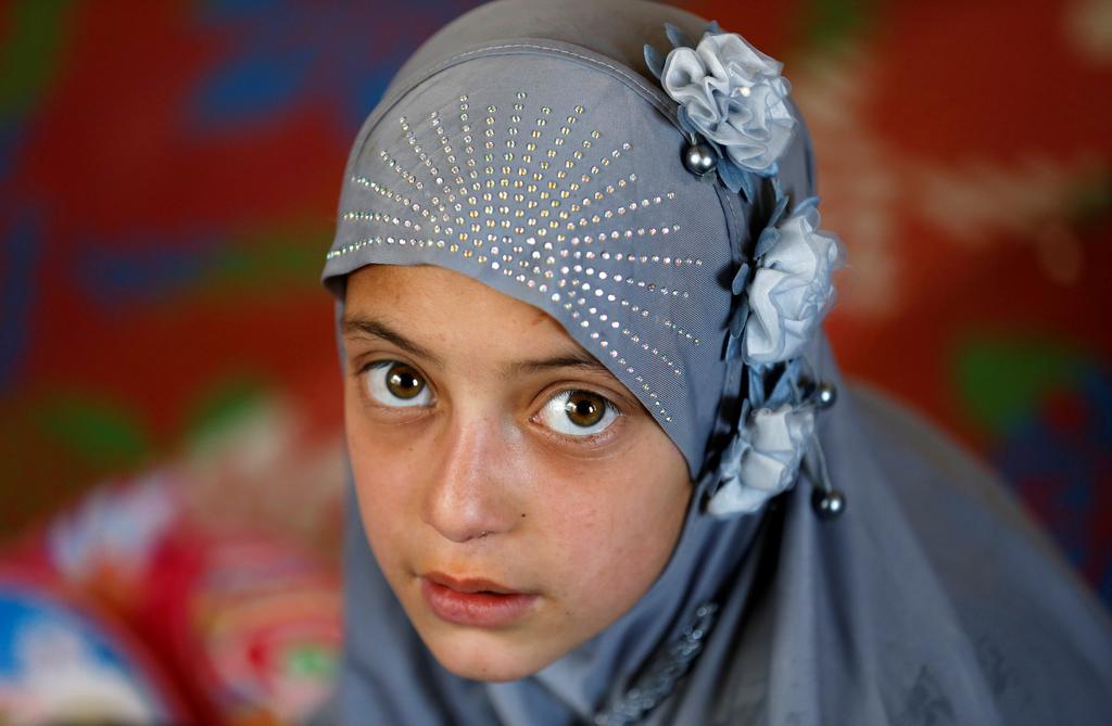 An internally displaced Afghan girl looks on as she attends a class inside a shelter at a refugee camp in Kabul, Afghanistan May 31, 2016. 