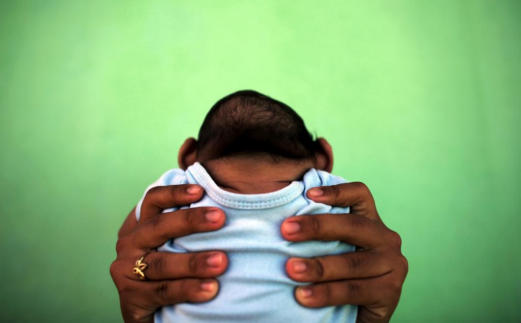 A 4-month-old baby born with microcephaly is held by his mother in front of their house in Olinda, near Recife, Brazil, February 11, 2016.