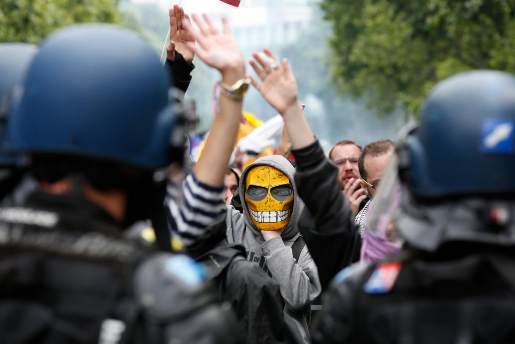 A masked youth reacts in front of French gendarmes during a demonstration in Paris.