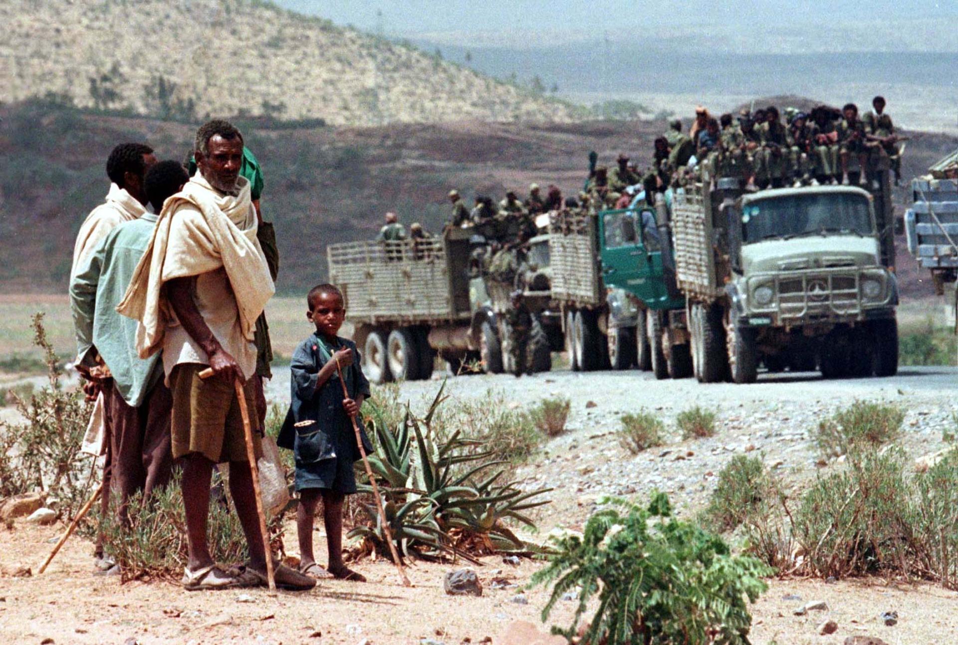Herdsmen watch a convoy carrying Ethiopian soldiers pass on its way to the frontline at Zalambessa, as Ethiopian and Eritrean forces clashed near the disputed town of Badme, June 11, 1998.