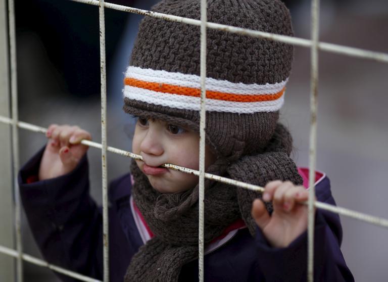 A Syrian boy looks through a gate as others wait to cross into Syria at the Oncupinar border crossing in Kilis, Turkey, Feb. 11, 2016.