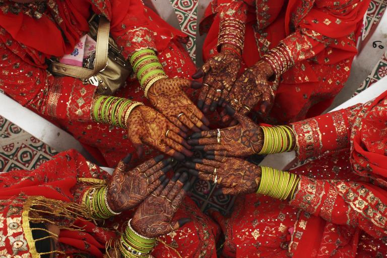 Brides display their hands painted with henna during a mass wedding ceremony in the western Indian city of Ahmedabad.