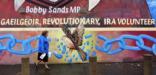 A woman carries a carton of milk past a Republican mural of "Gaeilgeoir" (Irish speaker) Bobby Sands outside the Sinn Fein offices on the Falls road in West Belfast (Reuters/Cathal McNaughton)