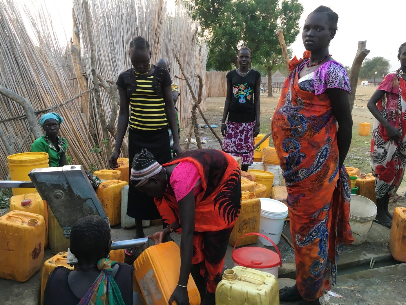 Women in Ganyiel stand in line waiting to pump water.