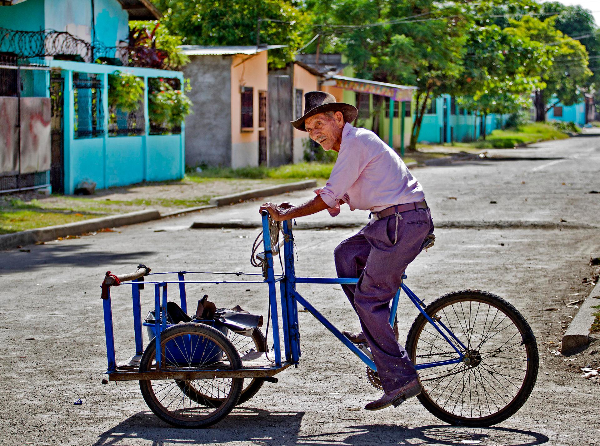 An elderly man rides his bike past colorful homes that were painted by the Honduran police in this once very dangerous Chamelecón neighborhood in San Pedro Sula, Honduras.