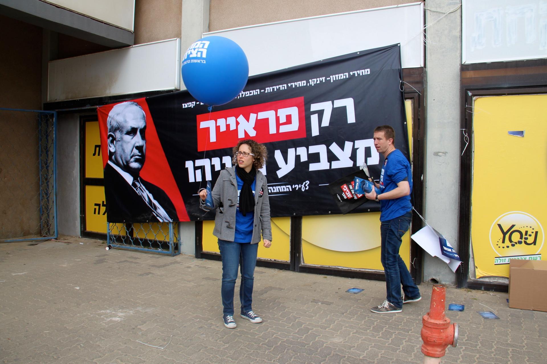 Staffers get ready for a Stav Shaffir campaign rally. Behind them is a banner knocking the competition. It says, 