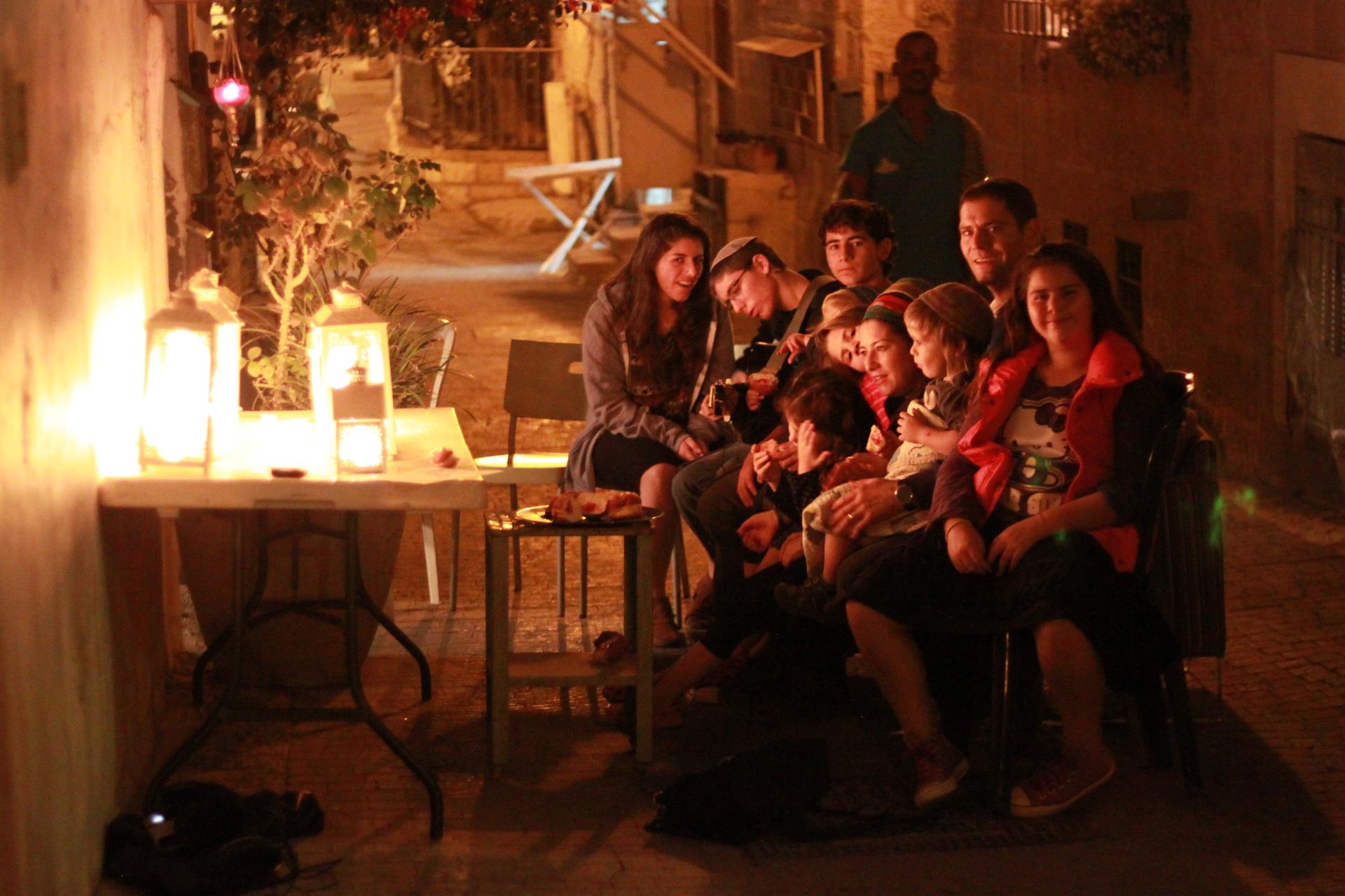 The Van Leeuwen family sits in front of the menorahs and sings.