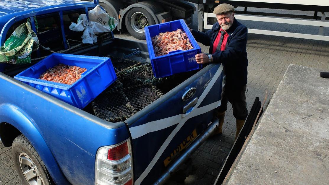 John Ogden, a former fisherman, picks up langoustines from a fisherman to sell at his seafood shack.