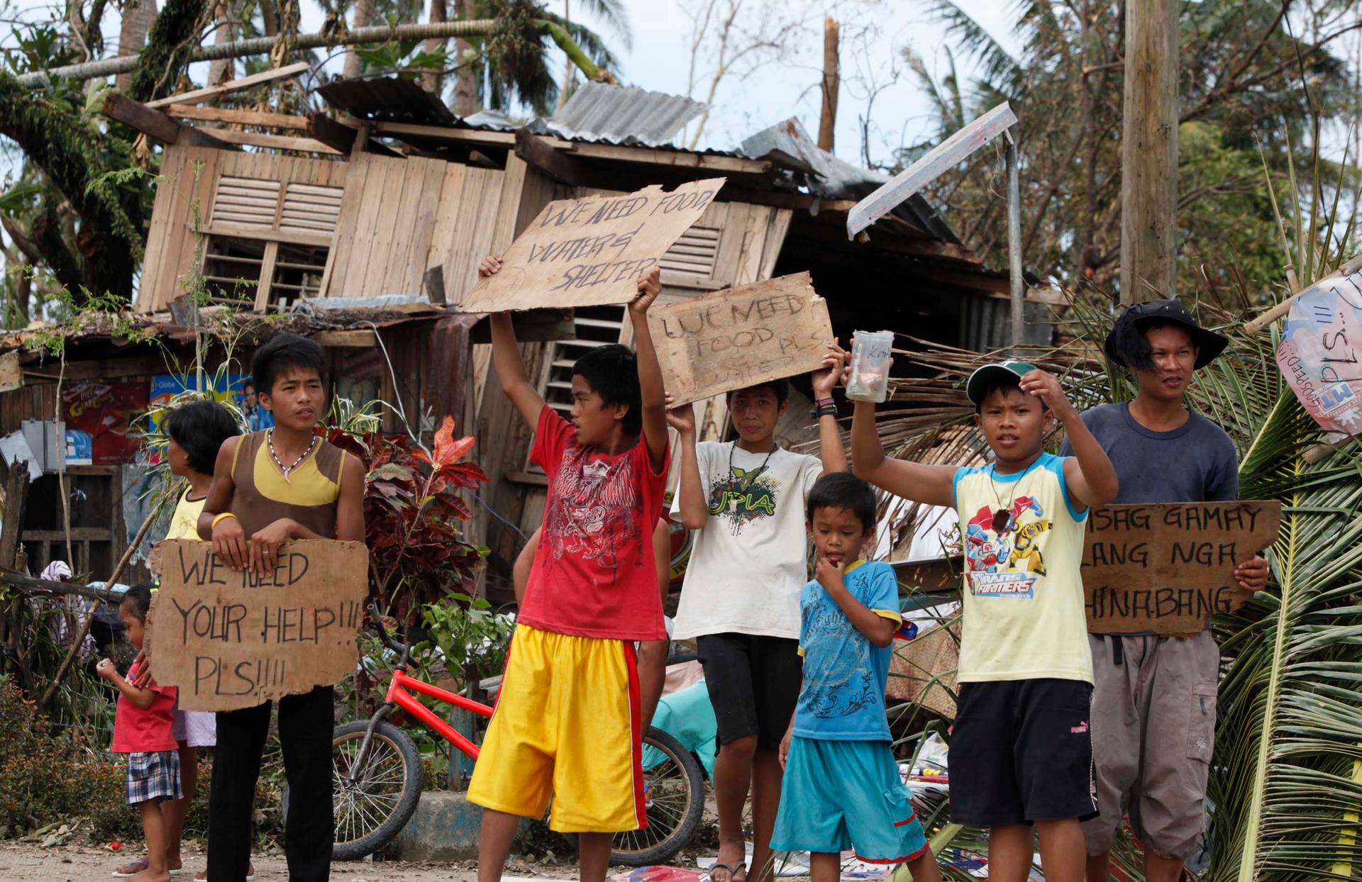Children hold signs asking for help and food along the highway, after Typhoon Haiyan hit Tabogon town in Cebu Province
