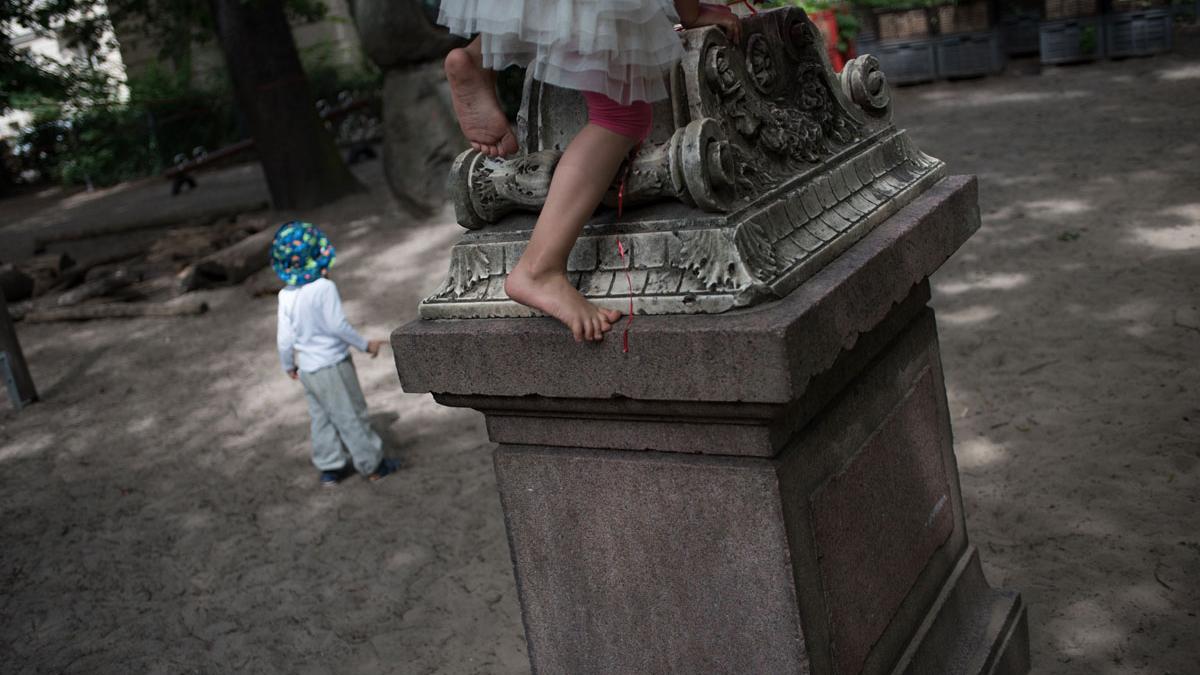 A pupil at the Sophienkirche day-care climbs atop a gravestone in the centers playground. The children are encouraged to explore the space, and not discouraged from climbing on some of the stones.