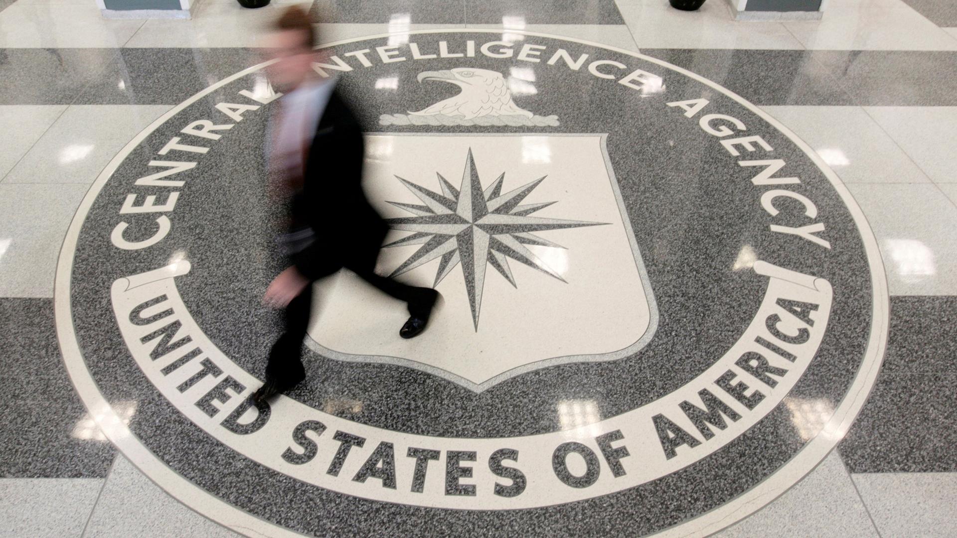 A man's image is blurred as he walks across a giant marble seal in the floor of the CIA headquarters in Langley, Virginia. 