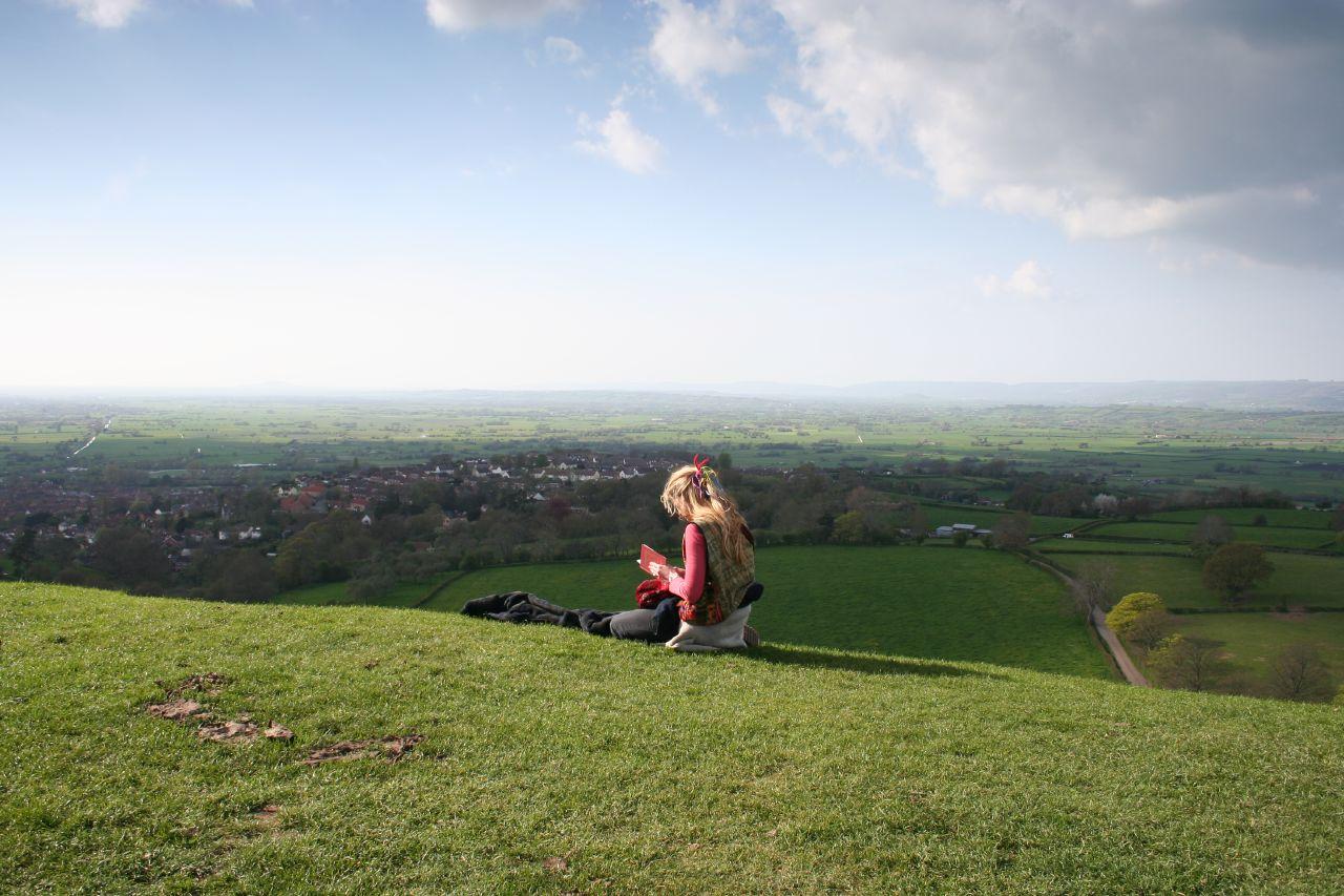 A girl reads on a hill in Glastonbury, England.