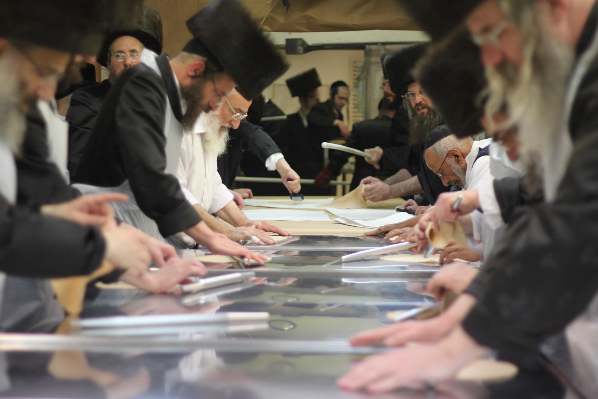 Men lined up in a human assembly line, preparing matzah at the Belz synagogue in Jerusalem.