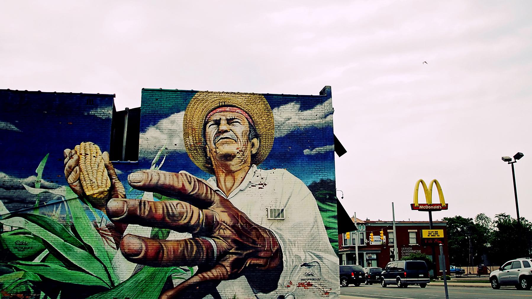 A mural of a farmer on a building, with a McDonald's in the background