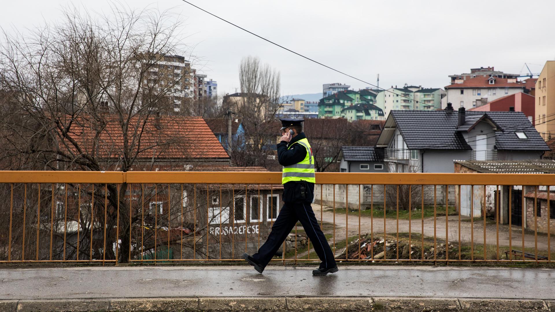 A Kosovo police officer crosses the bridge that connects north and south Mitrovica. The Ibar River serves as a natural divider in Mitrovica, where Serbs live on the northern side of the river and Albanians on the southern side.