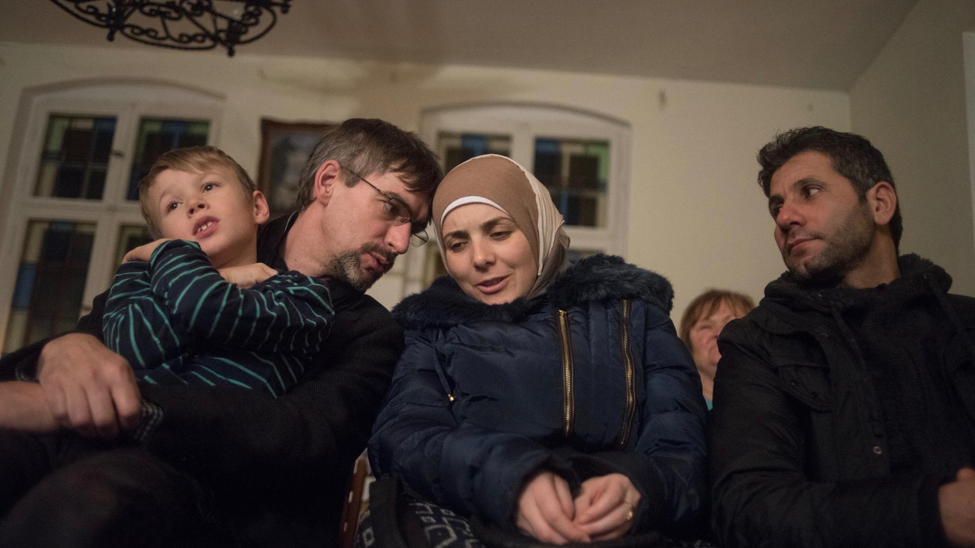 Golzow mayor Frank Schütz, left, leans over to whisper a question to Rasha Haimoud during a holiday concert. She and her husband, Ahmad Haimoud, are refugees who settled in the small former East German town after escaping the war in their native Syria