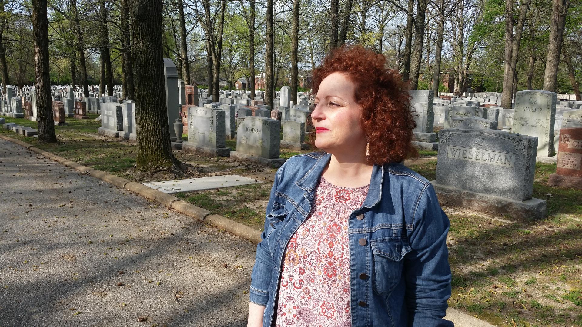 Karen Aroesty standing in front of the headstones of Chesed Shel Emeth cemetery