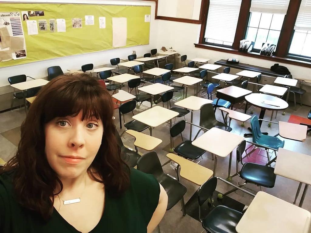 Teacher Suzanne Sutton takes a selfie in front of rows of empty desks at her classroom.