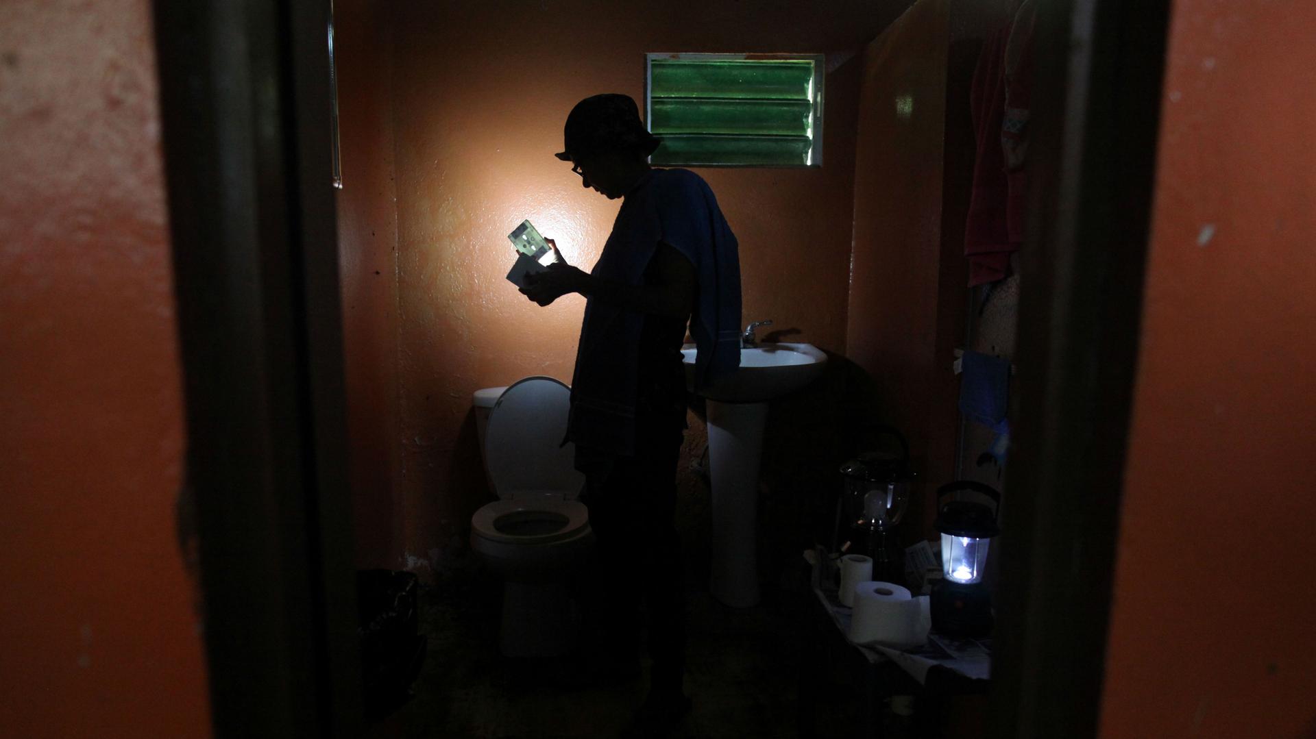  A woman uses a solar lamp inside the darkened bathroom of her home in Naguabo, Puerto Rico, on January 27, 2018. 