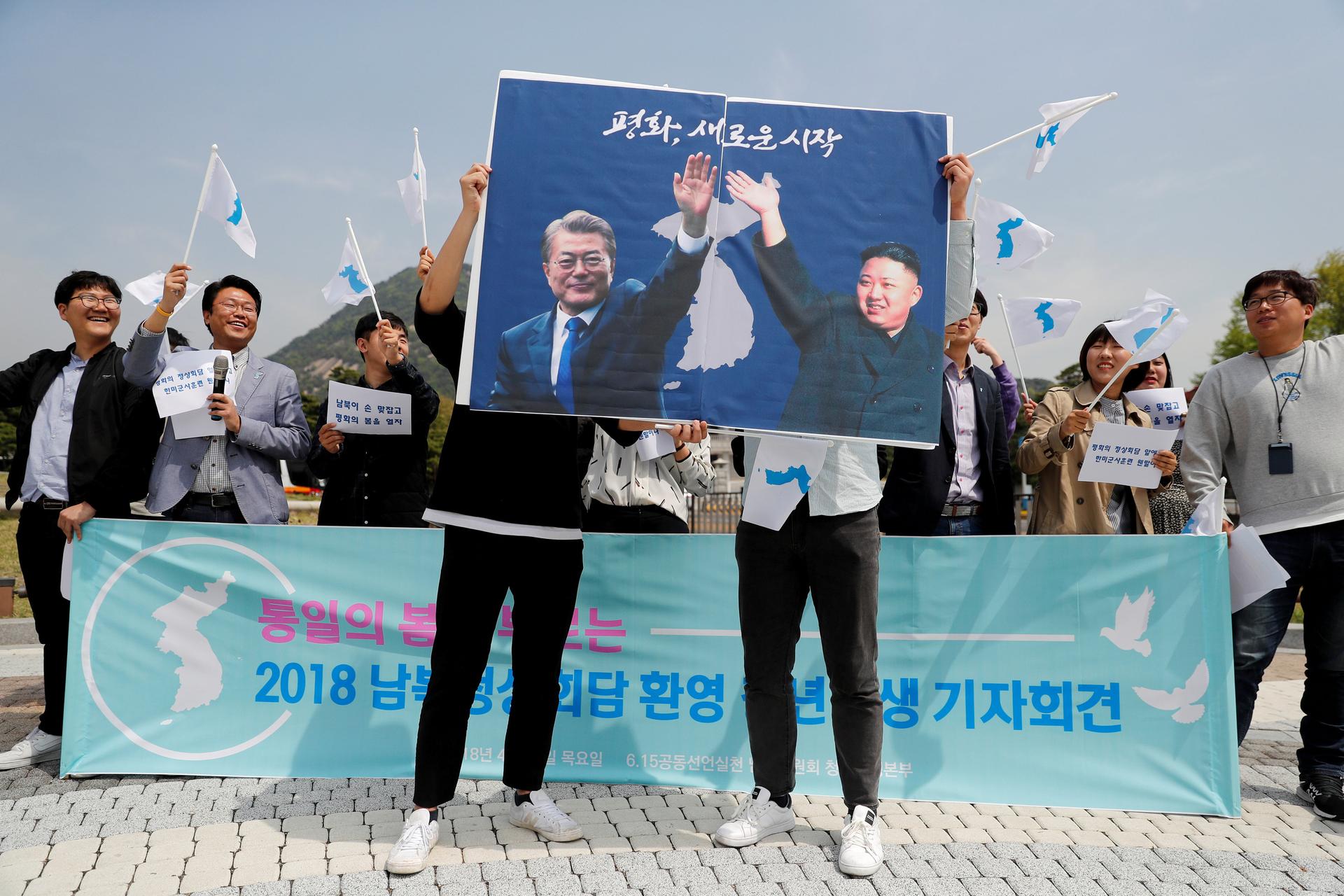 Students hold posters with pictures of South Korea's President Moon Jae-in and North Korea's leader Kim Jong Un 