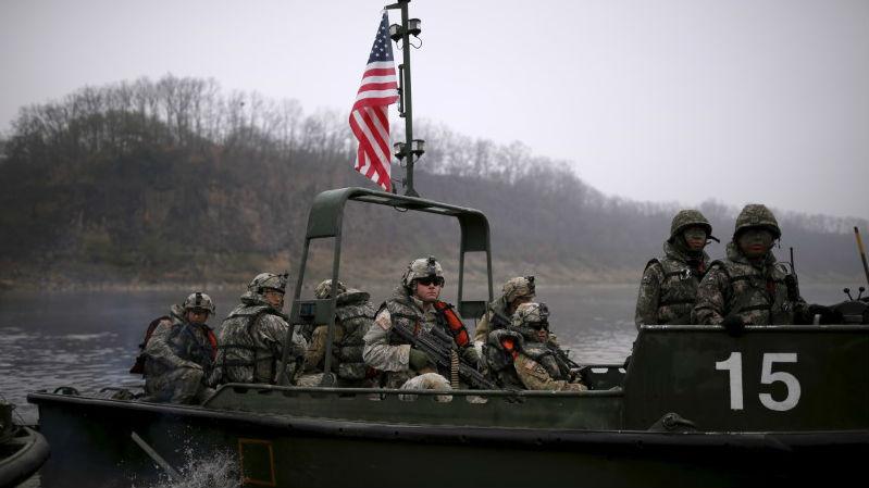 US army soldiers ride in a boat topped with an American flag while taking part in a US-South Korea joint river-crossing exercise near the demilitarized zone separating the two Koreas in Yeoncheon, South Korea, on April 8, 2016.