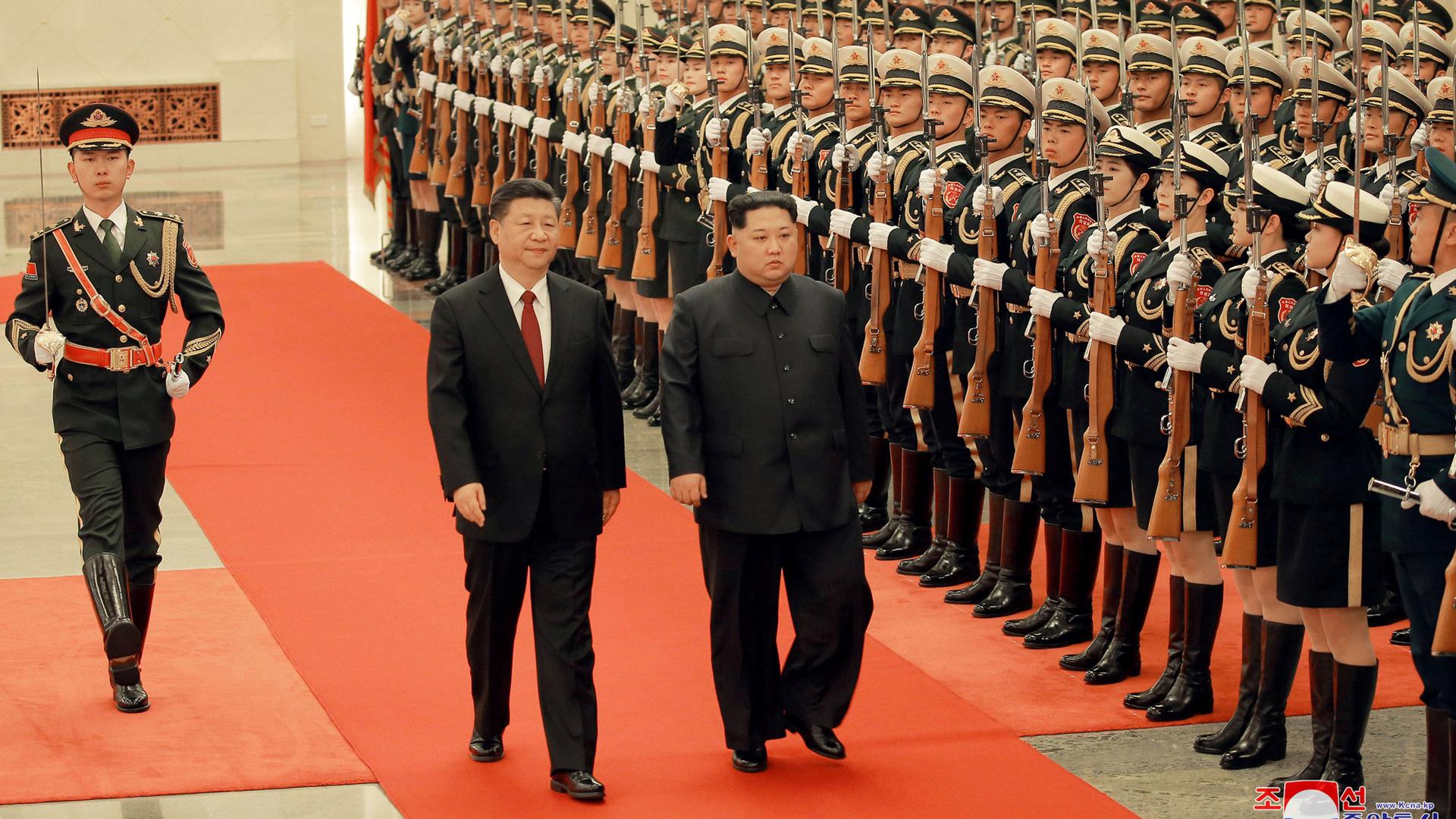 North Korean leader Kim Jong-un and Chinese President Xi Jinping walk past an rifle-clad honor guard.