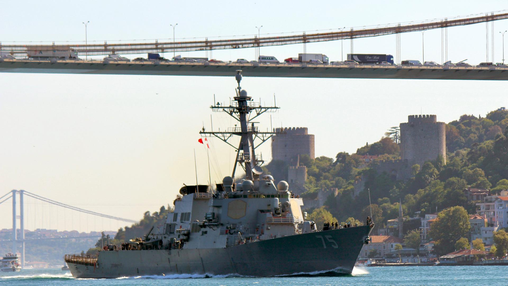 USS Donald Cook sails in the Bosphorus strait in Istanbul with a long cable bridge in the background.
