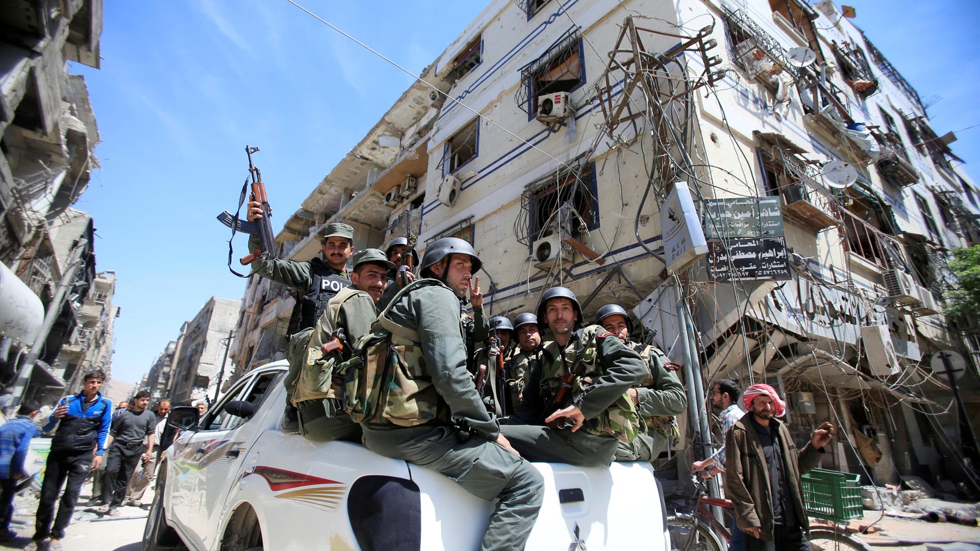 Syrian police hold weapons while they ride in the bed of a pickup truck in Doma.