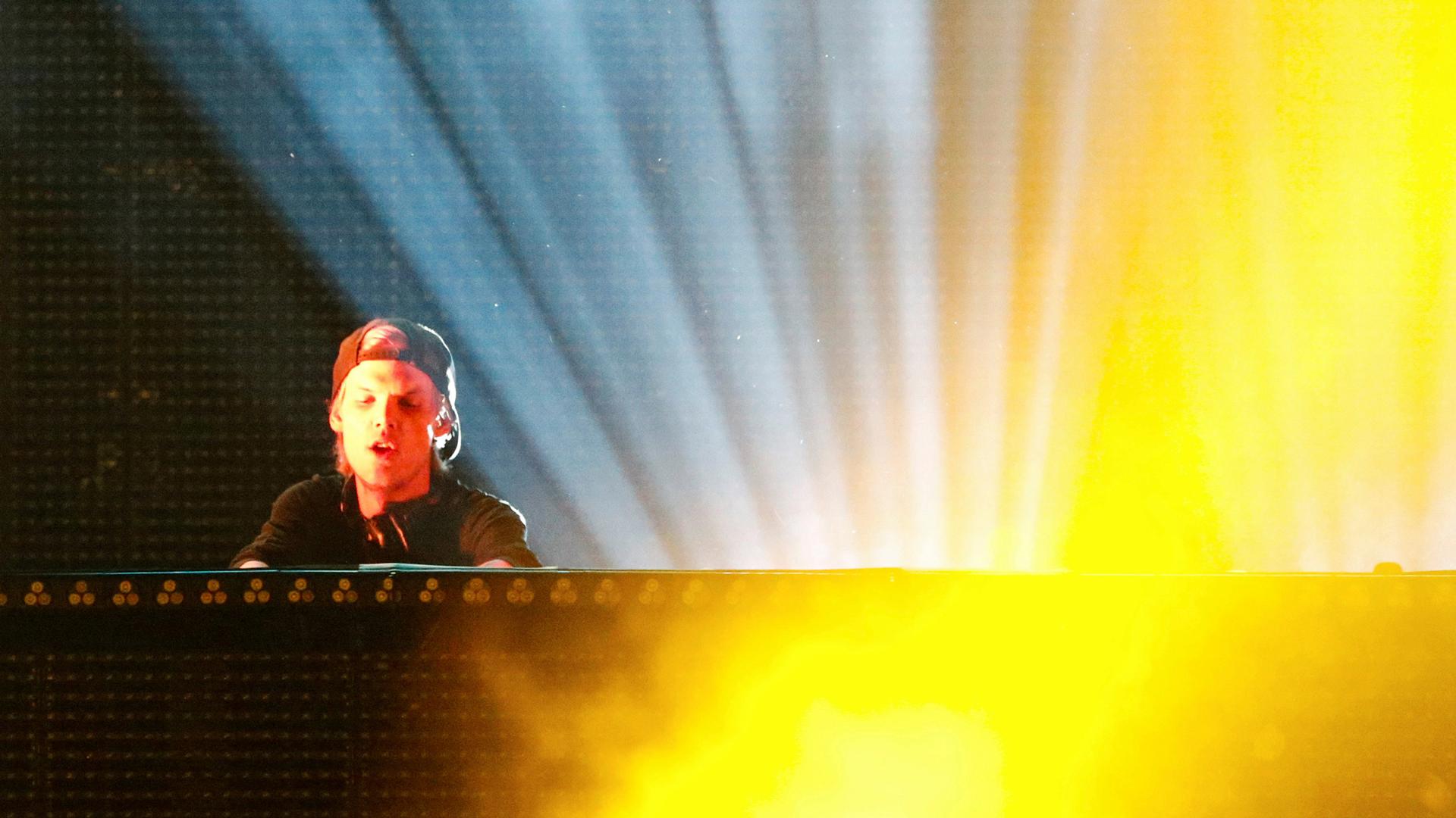 DJ Avicii performs while bright lights shine behind him during a concert at Brooklyn's Barclay's Center in New York.