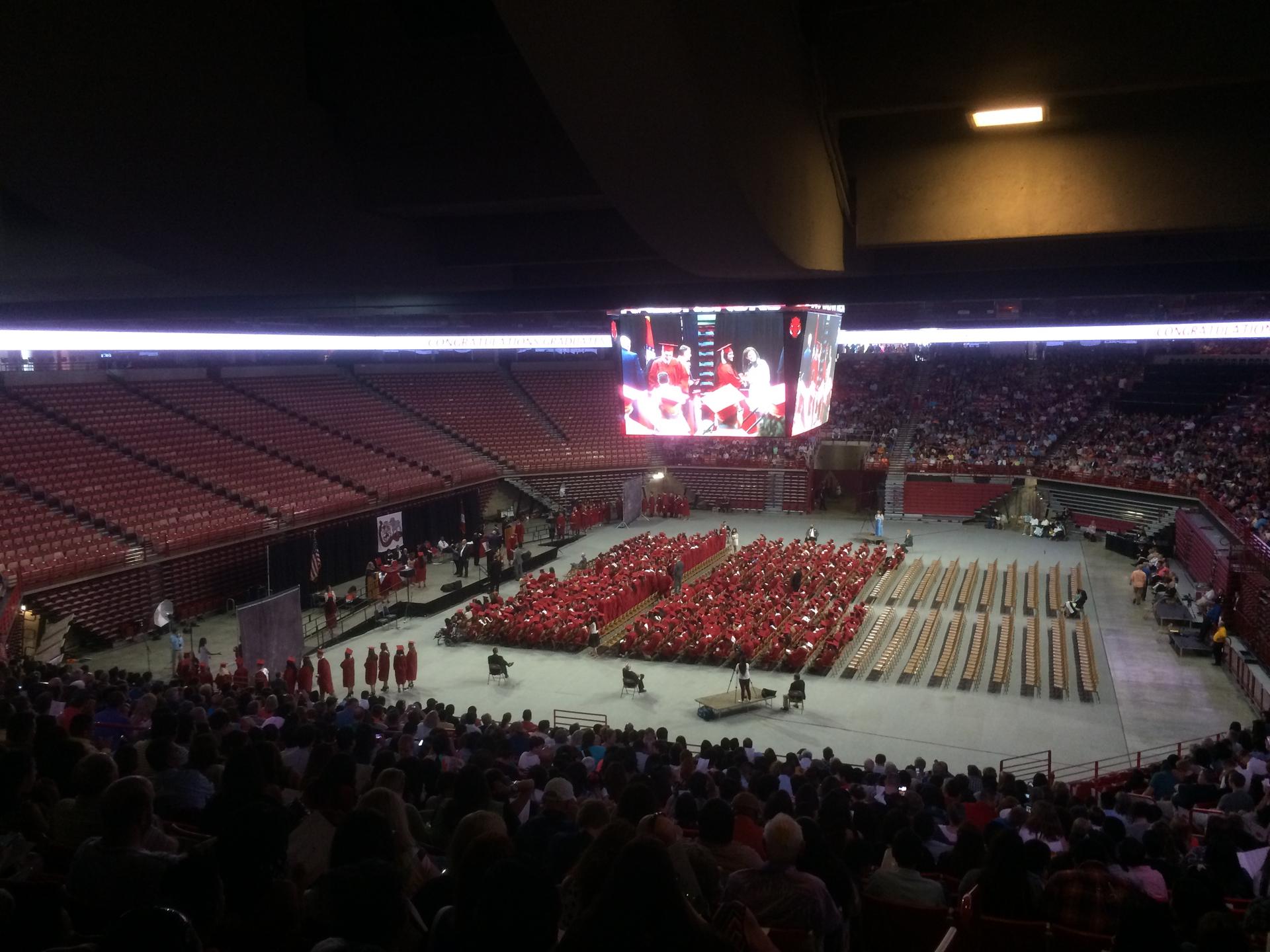 A big screen above a high school graduation ceremony in a stadium