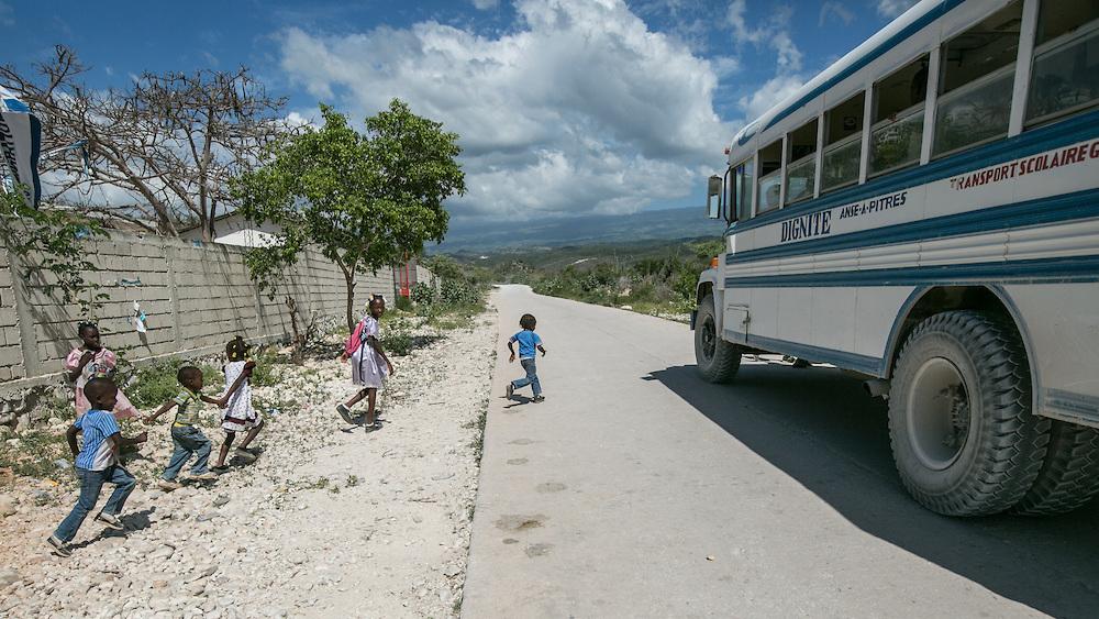 Migrant children board a bus outside the Notre Dame de Lourdes School in Anse-a-Pitres, Haiti, to return to their shelters after morning classes.