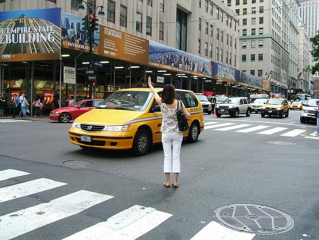 A woman hails a cab outside the Empire State Building in New York City.