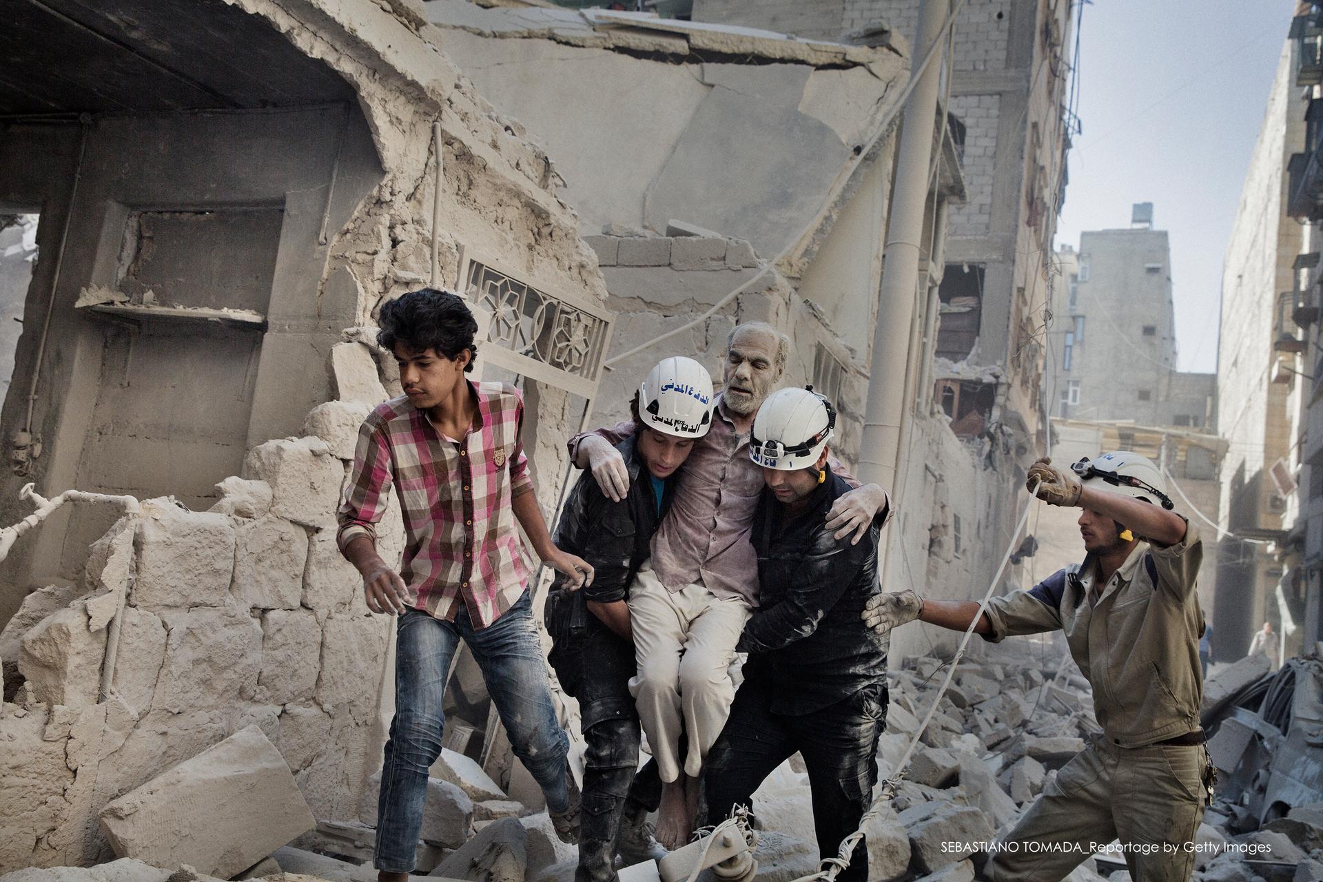 Members of the Hanano team rescue a man who had been trapped inside his home after a bomb hit it in Aleppo, Syria.