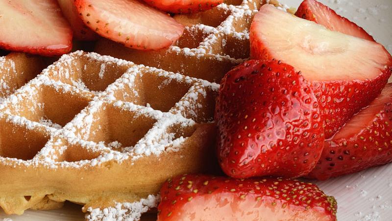 A Belgian waffle served traditionally with strawberries and confectioner's sugar. 