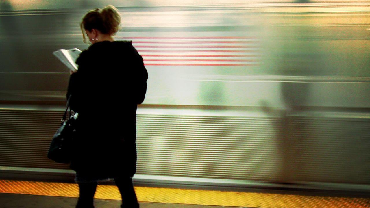 A woman reading on a New York City subway platform.