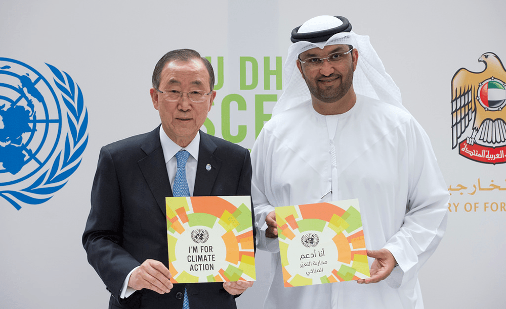 UN Secretary-General Ban Ki-moon and Sultan Ahmed al-Jaber, climate change envoy of the United Arab Emirates, hold up signs that read, "I'm for Climate Action", in English and Arabic, at a joint press conference in Abu Dhabi. 